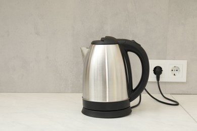 Photo of Modern electric kettle on counter in kitchen. Space for text