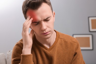 Young man suffering from headache in room