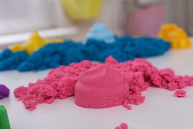 Photo of Colorful kinetic sand on white table indoors