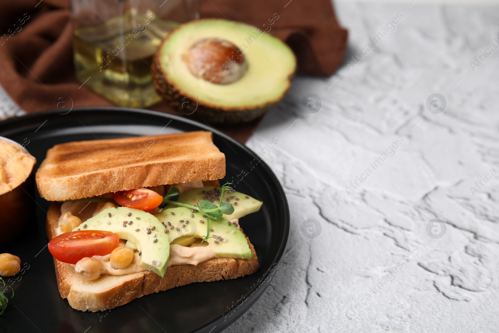 Photo of Delicious sandwich with hummus and vegetables, ingredients on white textured table. Space for text