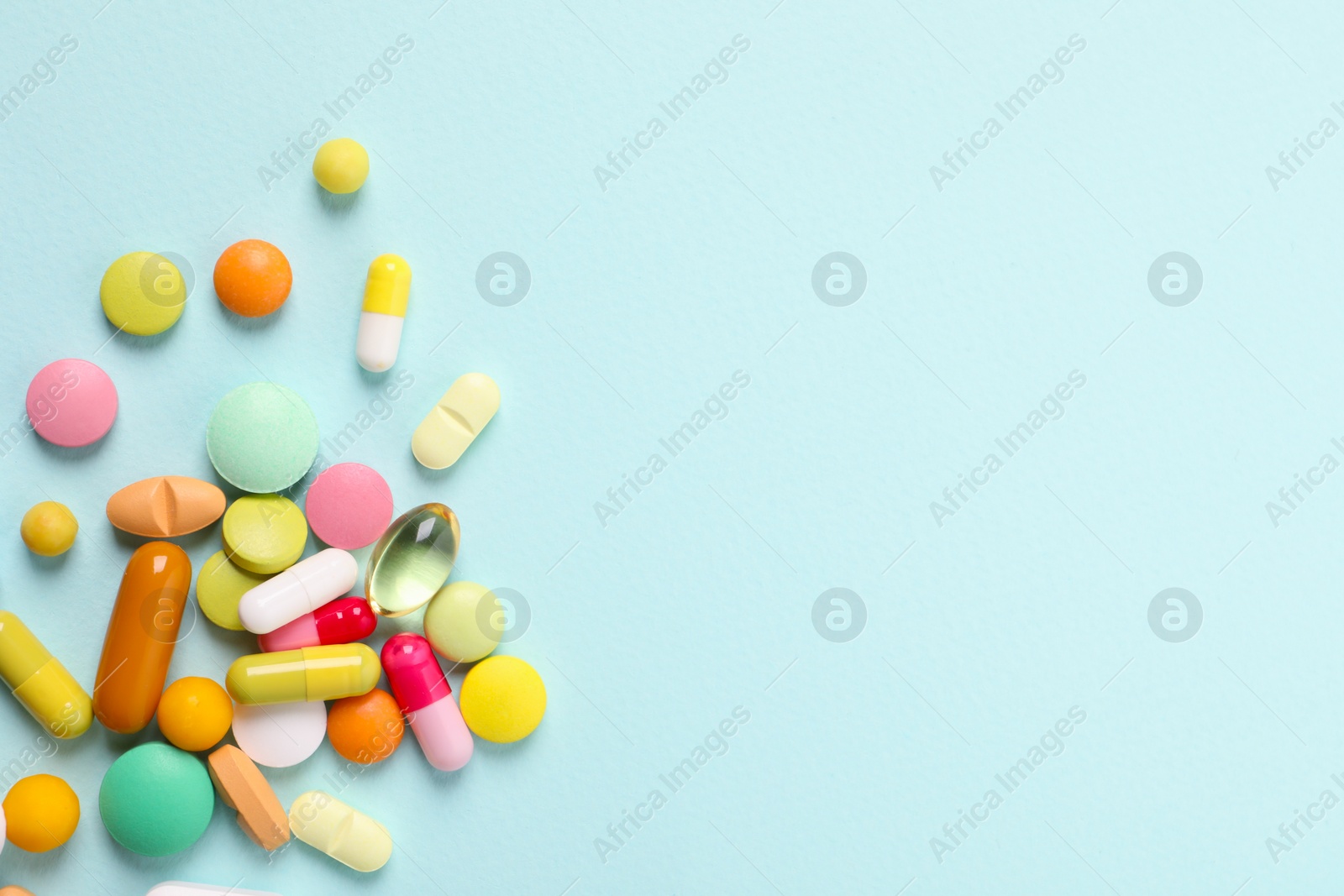 Photo of Many different pills on light blue background, flat lay. Space for text