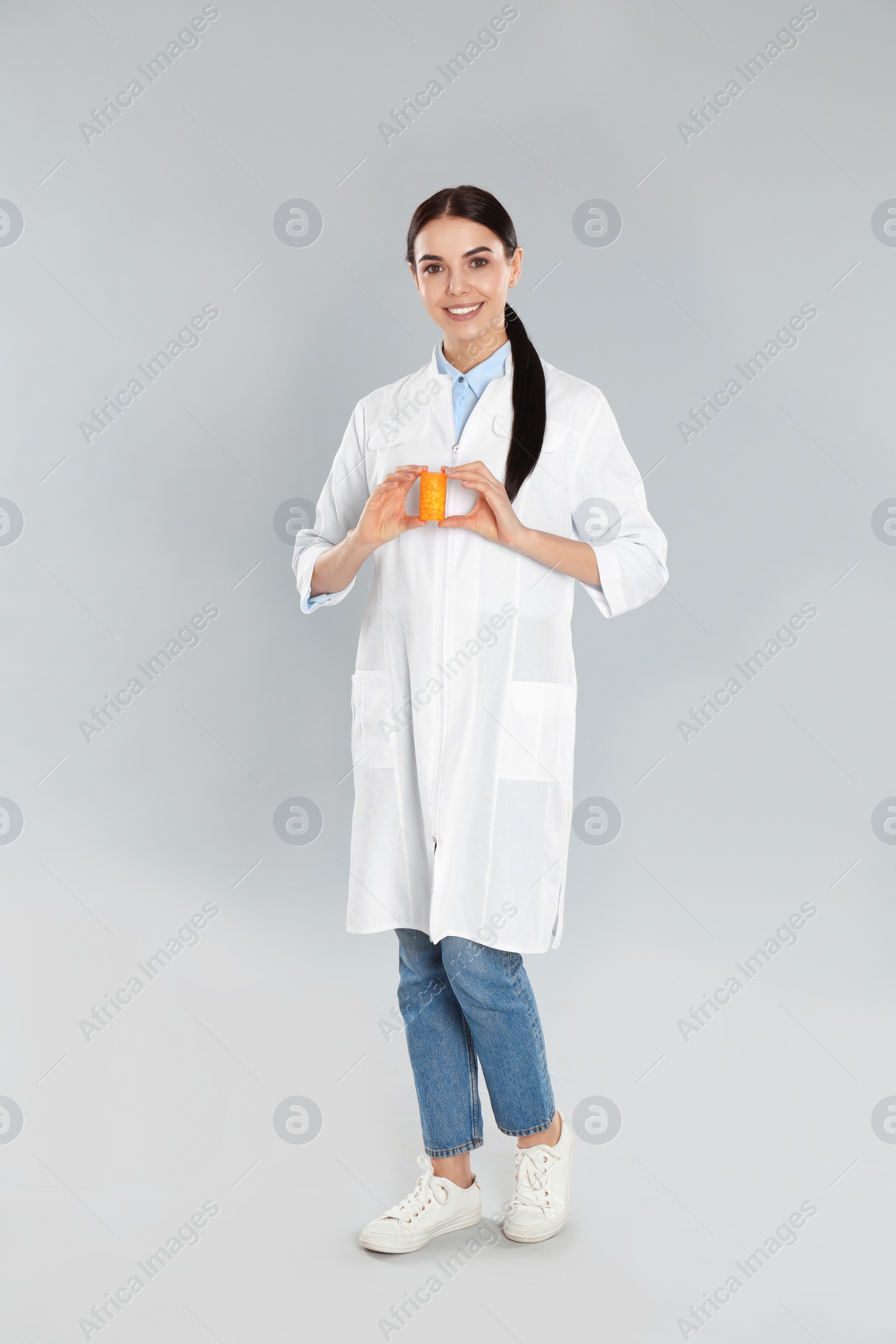 Photo of Professional pharmacist with pills on light grey background