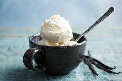 Photo of Cup with tasty vanilla ice cream on wooden table