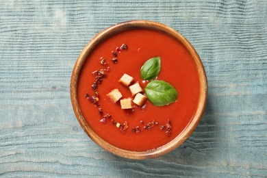 Bowl with fresh homemade tomato soup on wooden background, top view