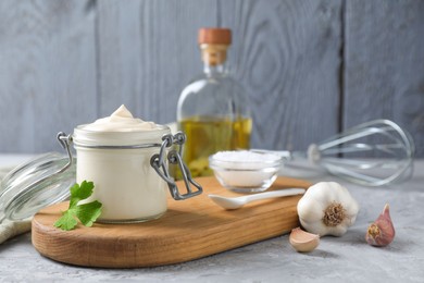 Photo of Tasty mayonnaise in jar and ingredients on gray table, closeup