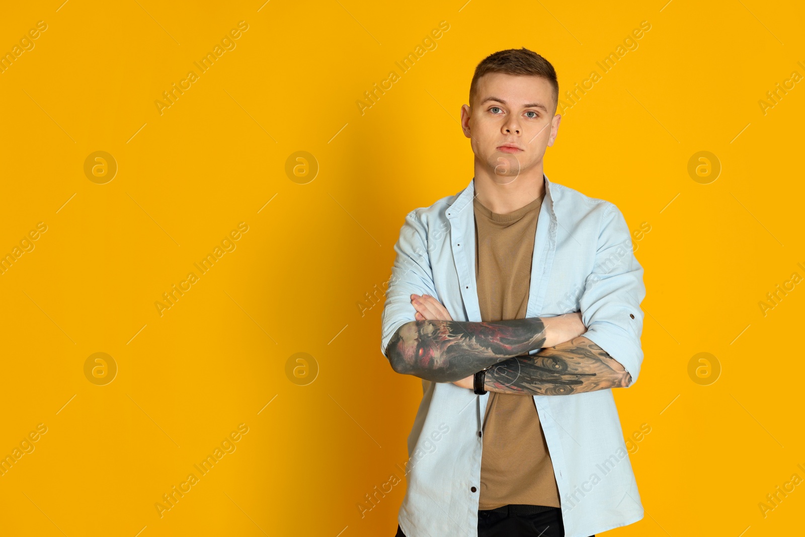 Photo of Young man with tattoos on yellow background. Space for text