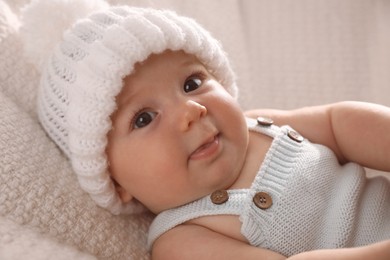 Photo of Cute little baby wearing white warm hat on knitted blanket, closeup