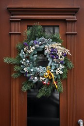 Photo of Beautiful Christmas wreath hanging on wooden door