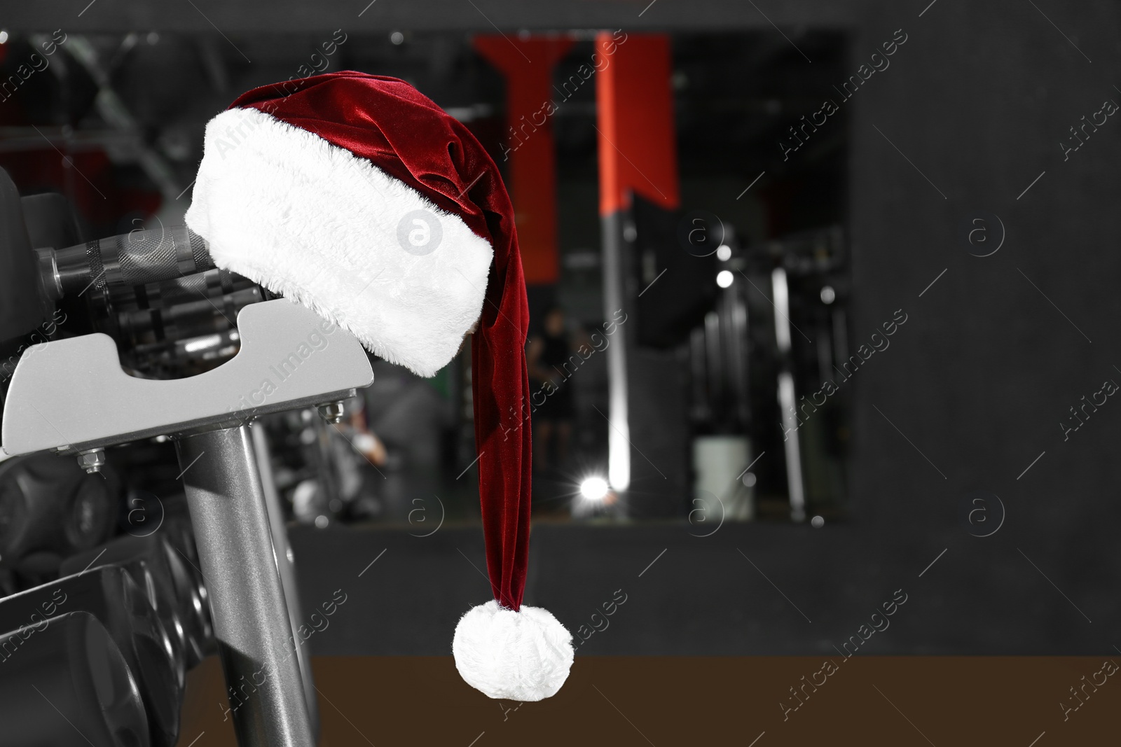 Photo of Santa hat on stand with dumbbells in modern gym