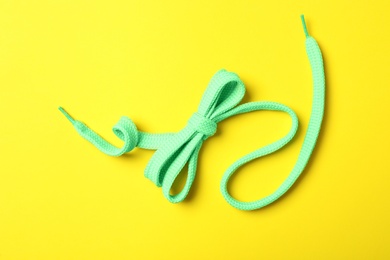 Photo of Green shoelace on yellow background, top view