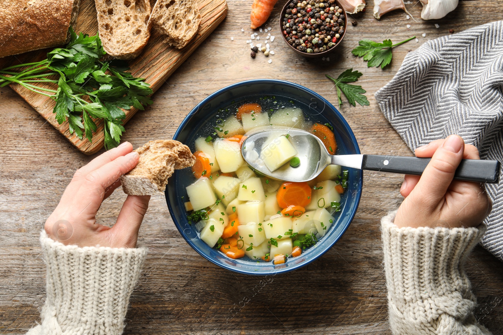 Photo of Woman eating fresh homemade vegetable soup at wooden table, top view