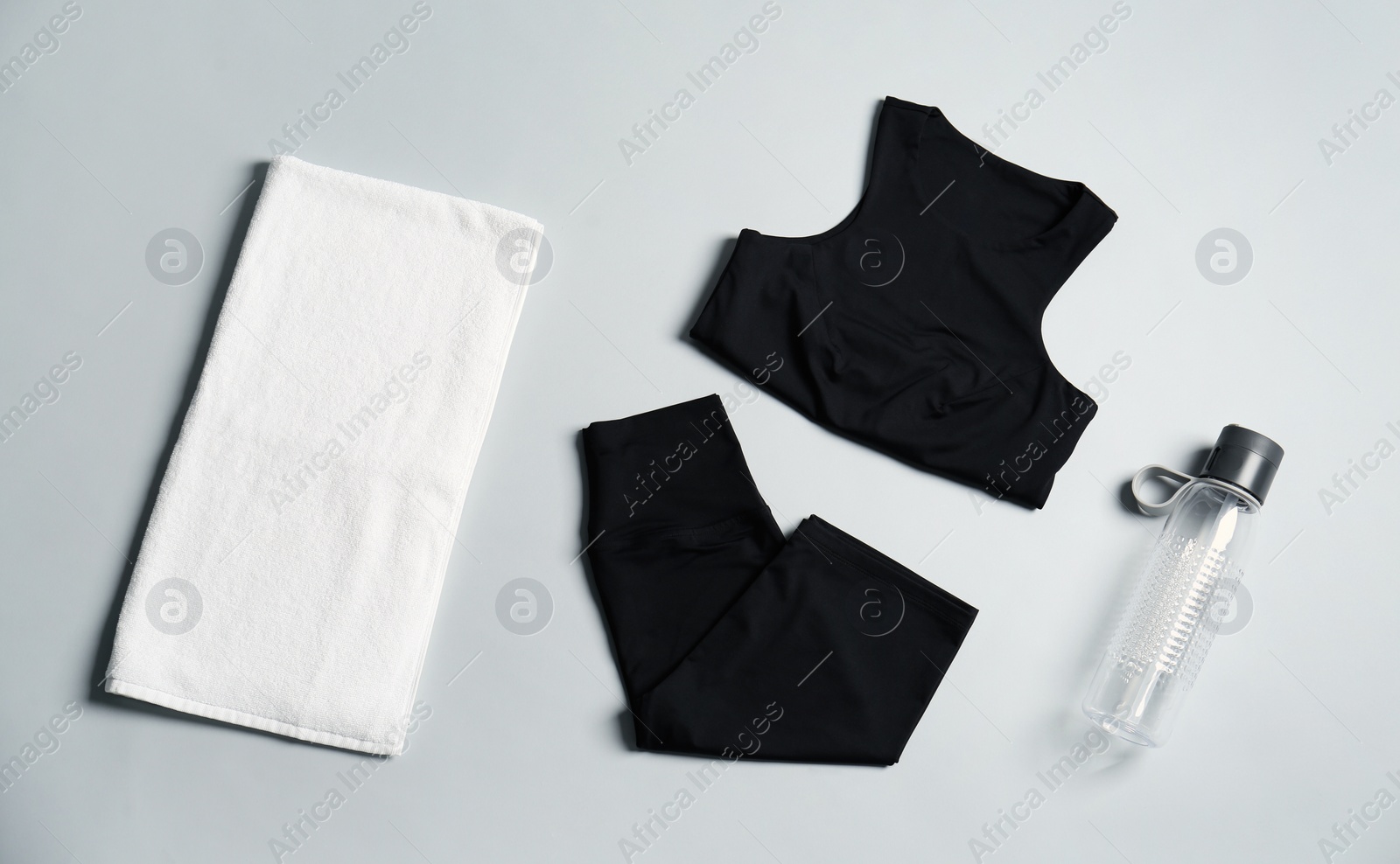 Photo of Sportswear, bottle of water and towel on grey background, flat lay. Yoga equipment