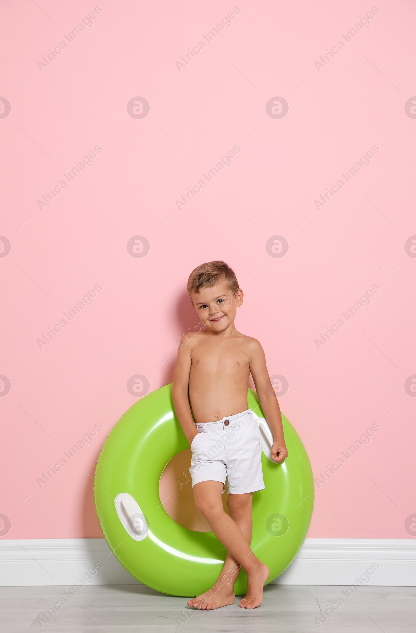 Photo of Cute little boy with bright inflatable ring near color wall