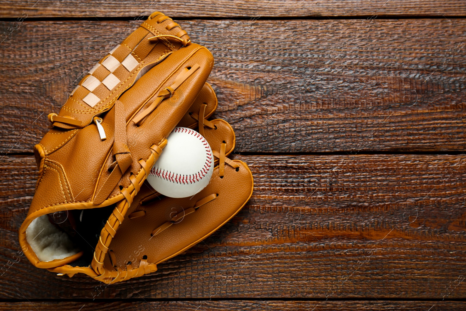 Photo of Leather baseball glove with ball on wooden table, top view. Space for text