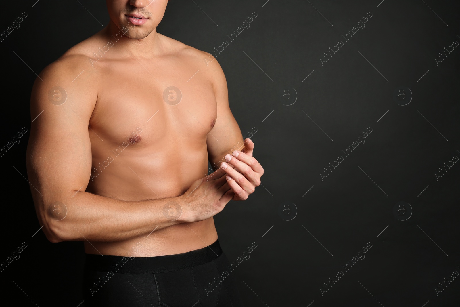 Photo of Man with sexy body on black background, closeup. Space for text
