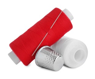 Thimble and spools of sewing threads with needle isolated on white