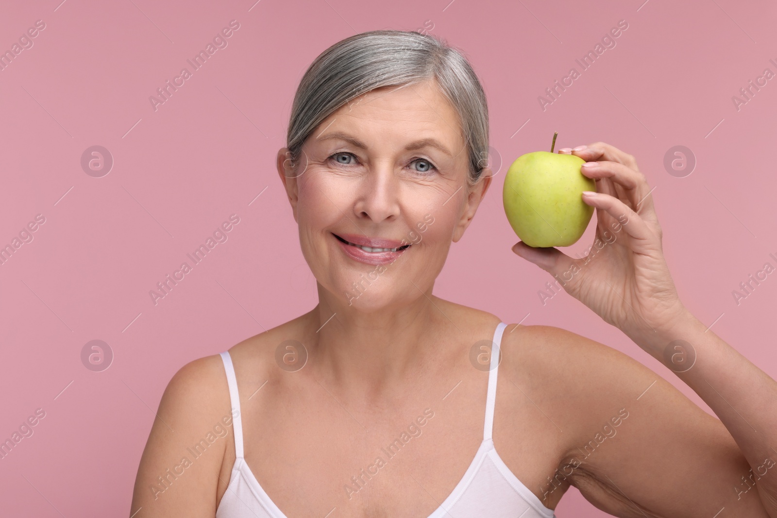 Photo of Beautiful woman with fresh apple on pink background. Vitamin rich food