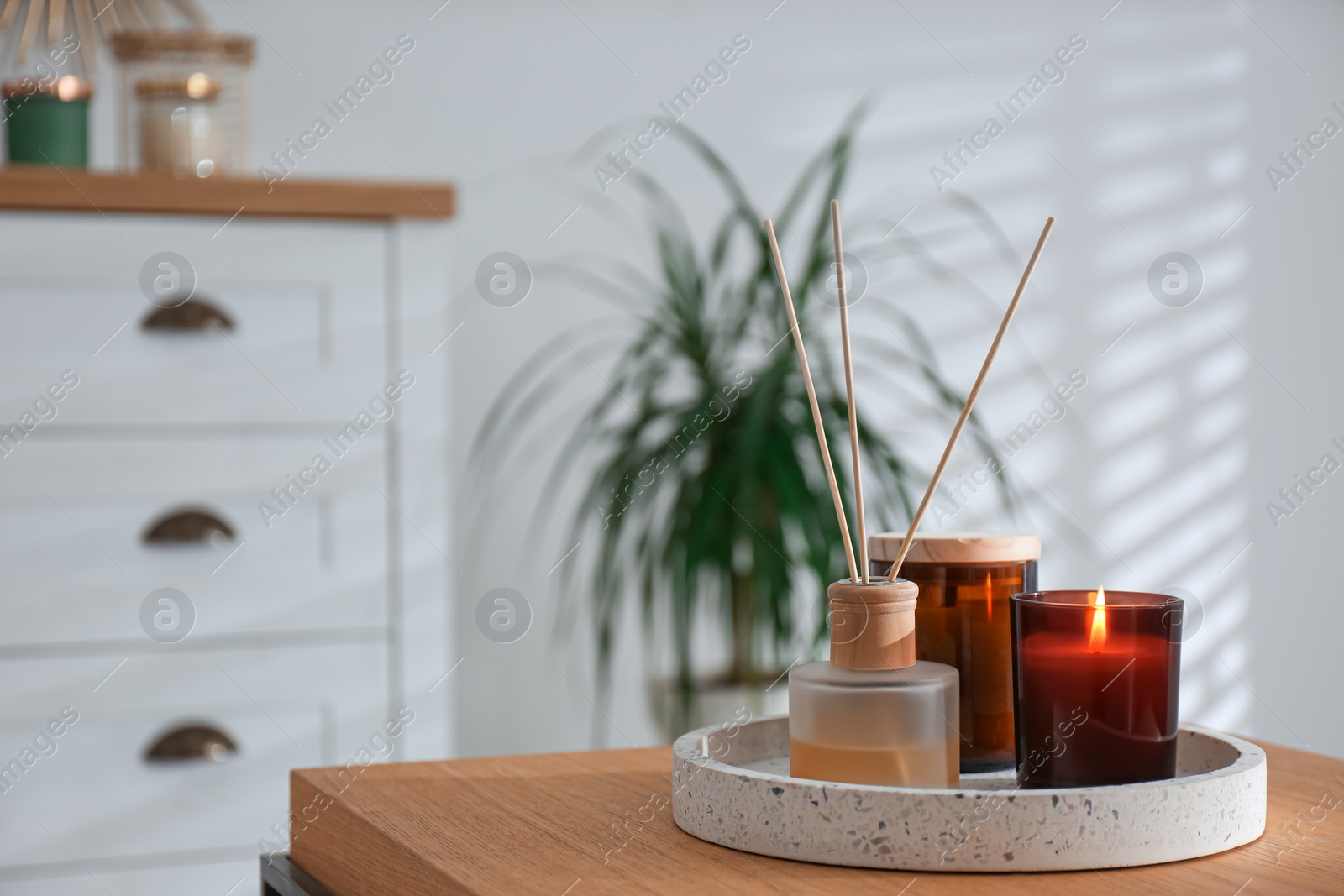 Photo of Air reed freshener and candles on table in living room. Space for text