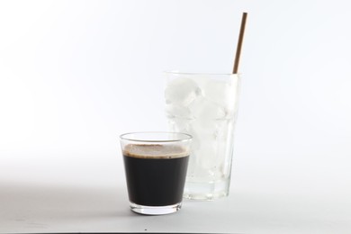 Photo of Coffee and ice cubes in different glasses on white background