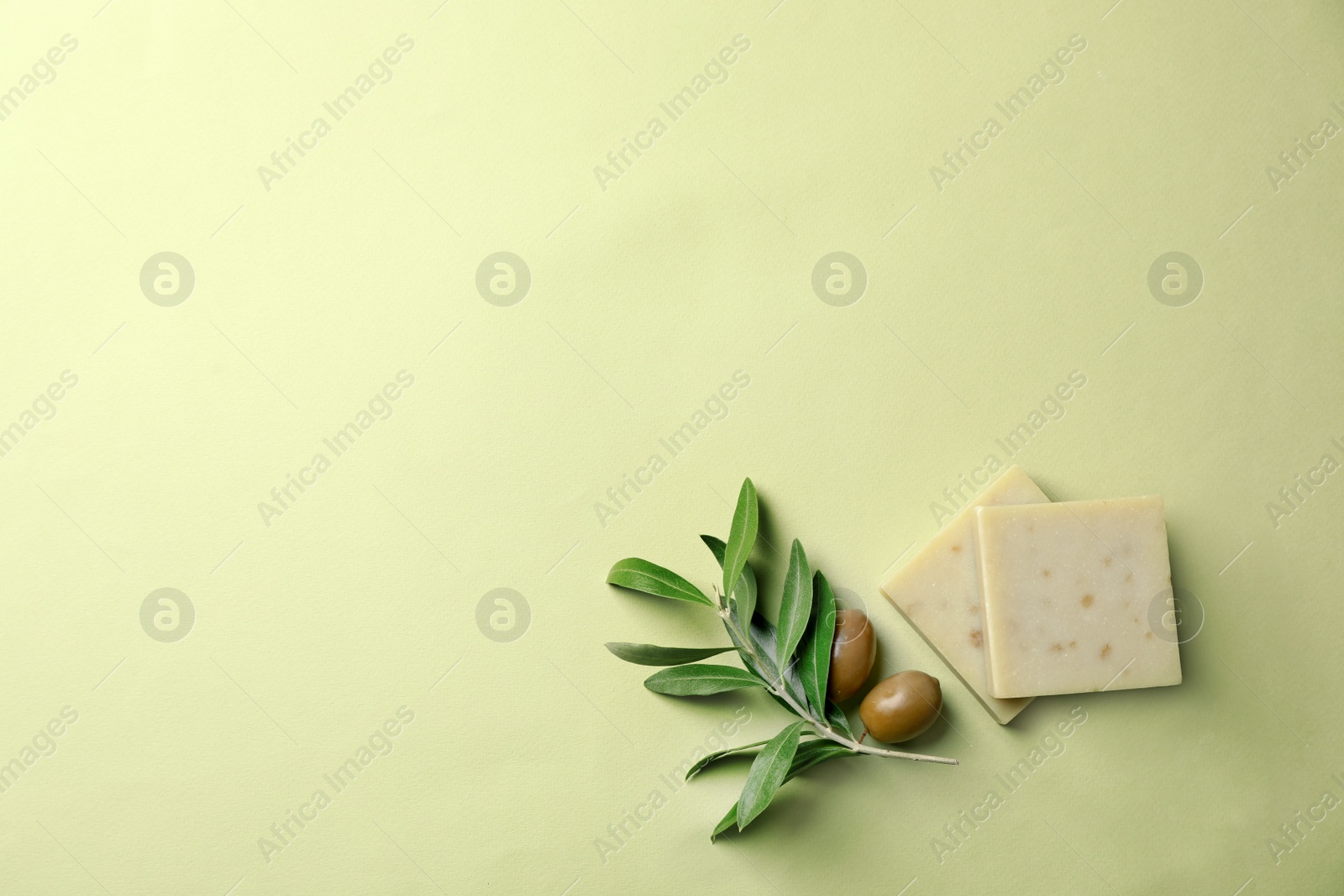 Photo of Handmade soap bars and leaves with olives on color background, top view with space for text