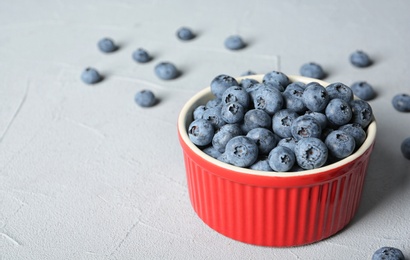 Photo of Crockery with juicy and fresh blueberries on color table