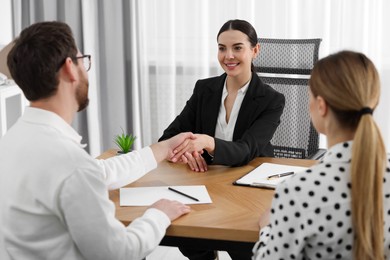 Lawyer shaking hands with clients in office