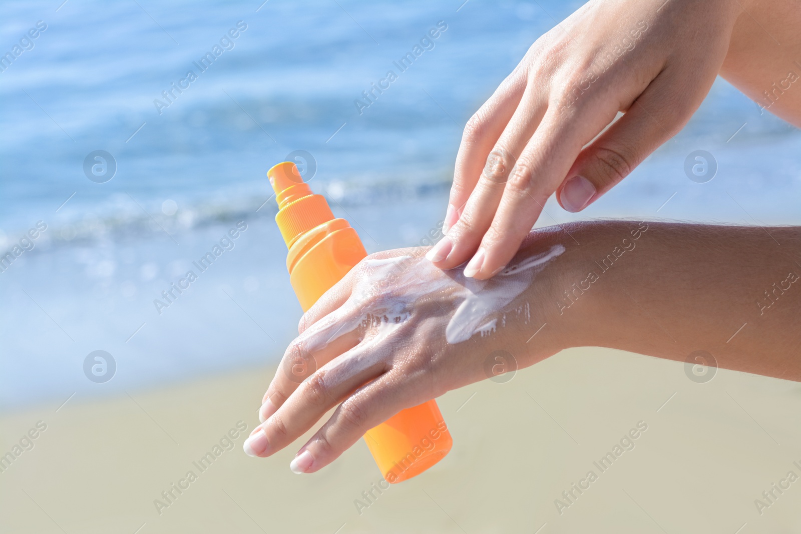 Photo of Woman applying sun protection cream on her hand at beach, closeup