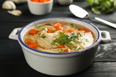 Photo of Dish with fresh homemade chicken soup on wooden table, closeup