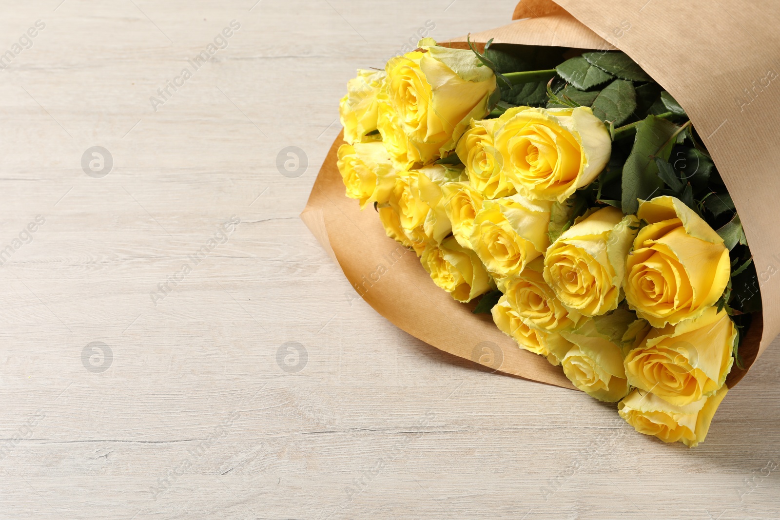 Photo of Beautiful bouquet of yellow roses on wooden table, space for text