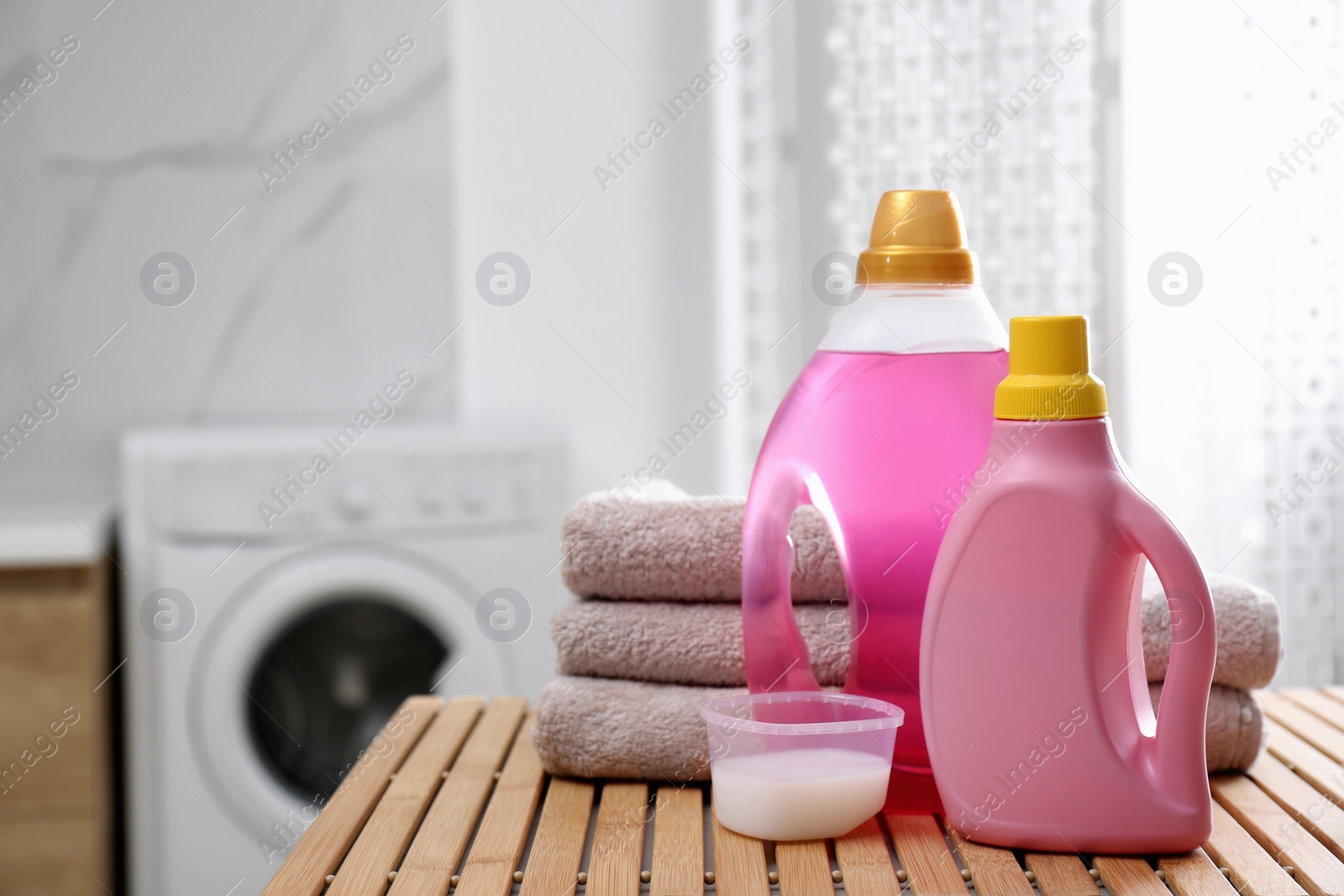 Photo of Stack of folded towels and detergents on wooden table in bathroom