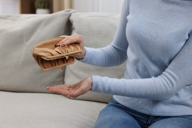 Photo of Woman with empty wallet on sofa indoors, closeup