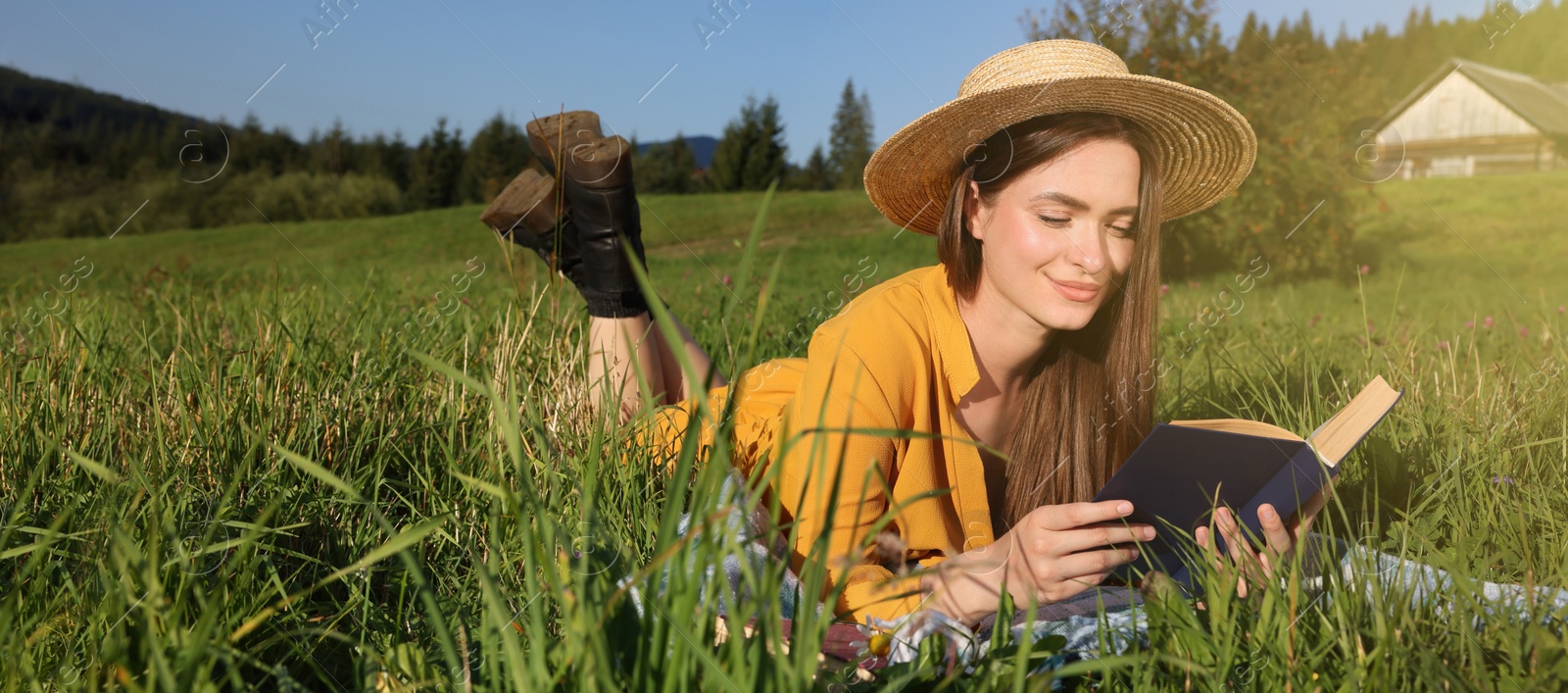 Image of Beautiful young woman reading book on green meadow. Banner design