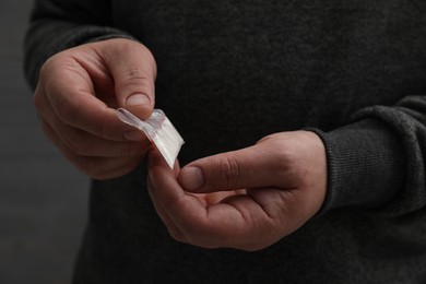 Photo of Drug addiction. Man with plastic bag of cocaine on grey background, closeup