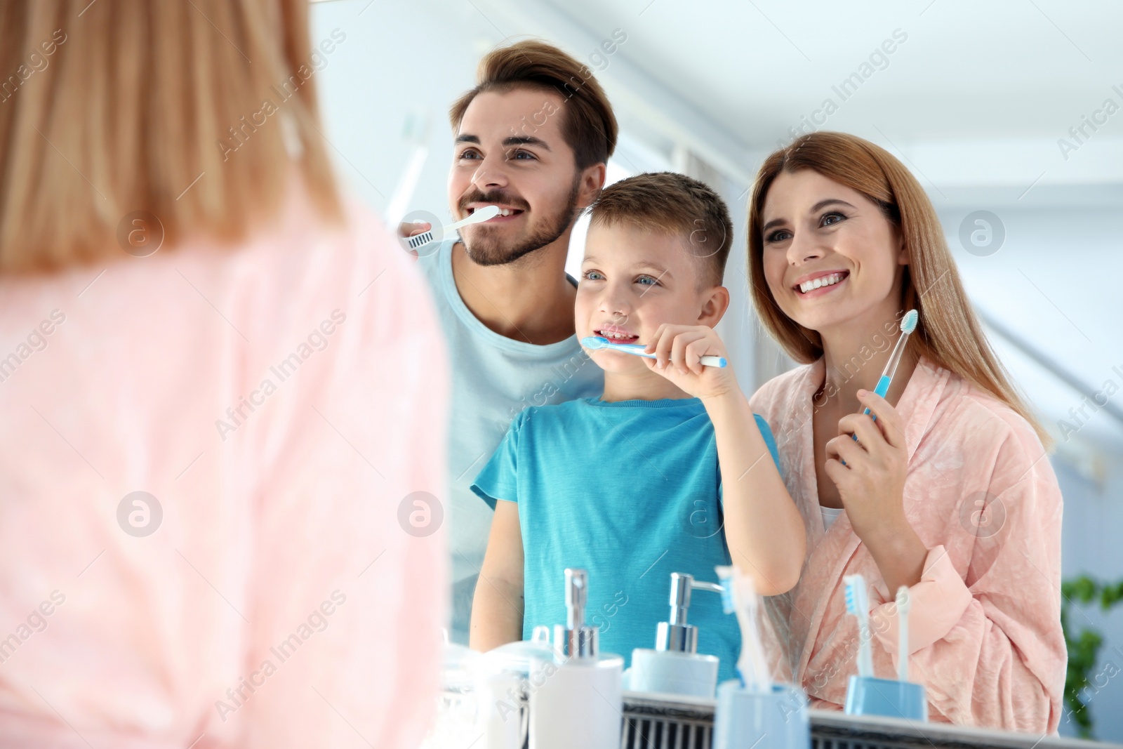 Photo of Happy family with toothbrushes near mirror in bathroom. Personal hygiene