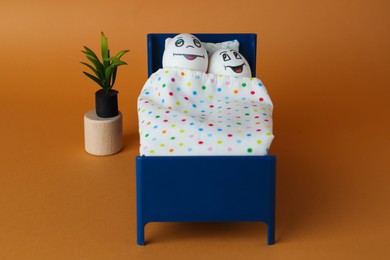Photo of Eggs with drawn happy faces in small bed on orange background