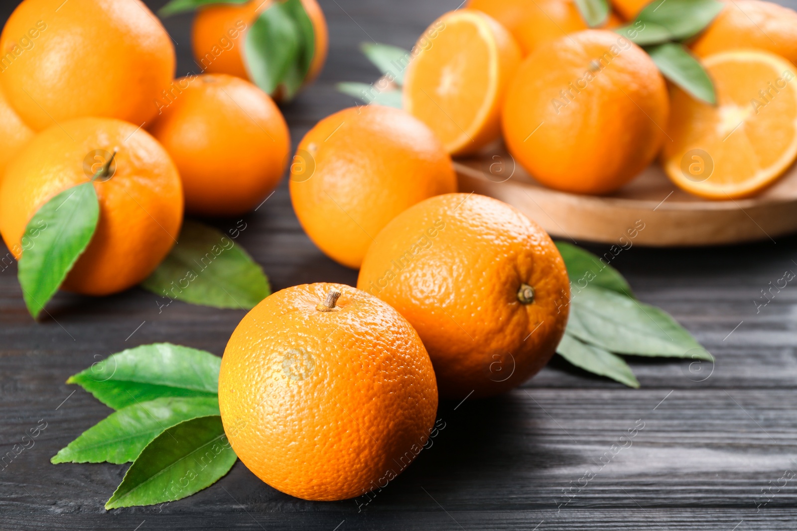 Photo of Delicious ripe oranges on black wooden table