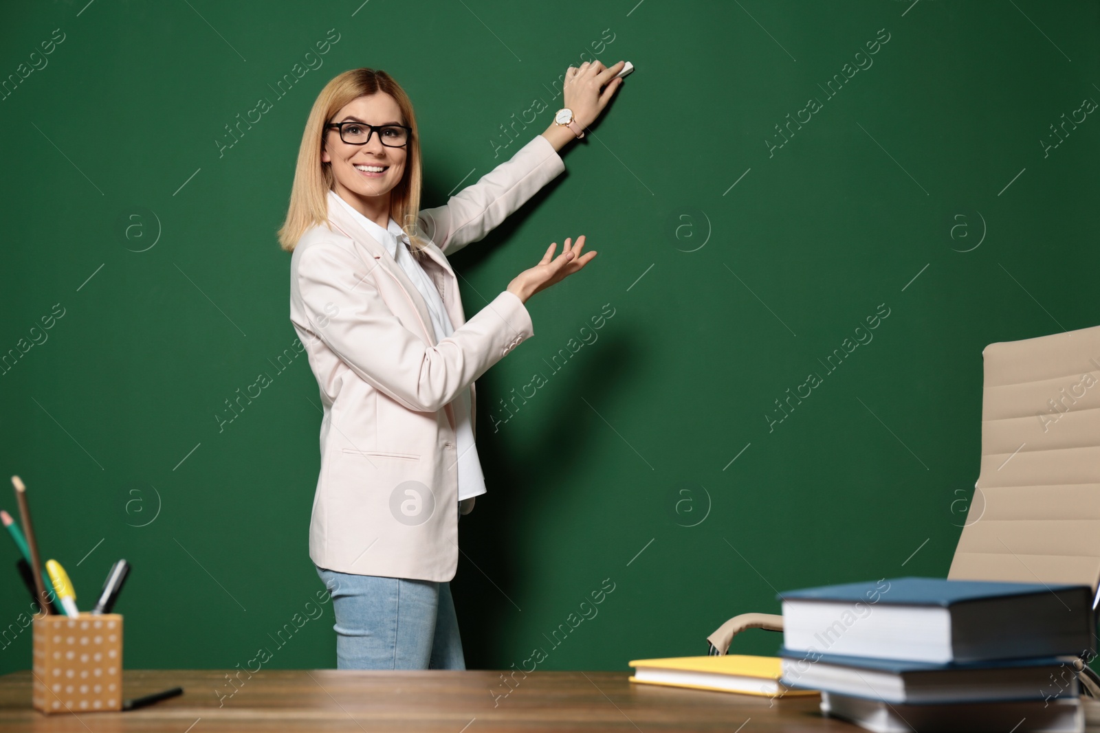 Photo of Beautiful teacher writing on chalkboard, space for text