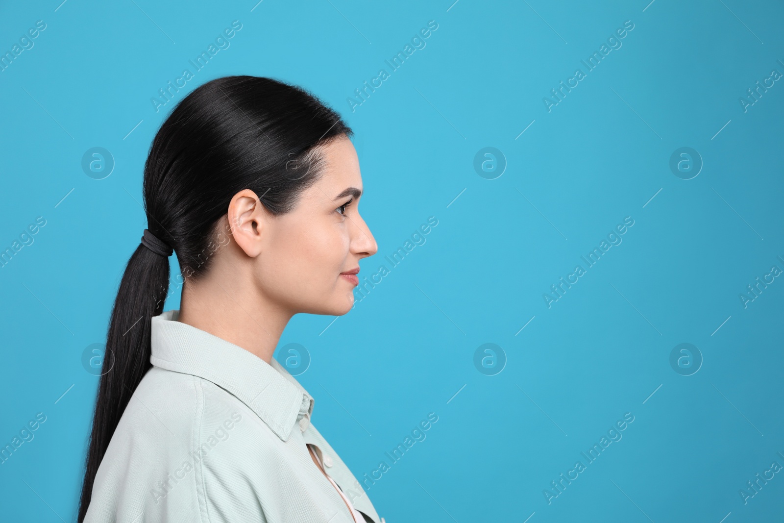 Photo of Profile portrait of young woman on light blue background. Space for text