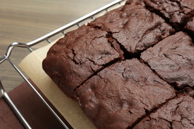 Photo of Cooling rack with delicious freshly baked brownies on wooden table, closeup