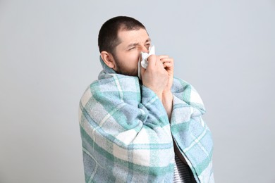 Photo of Man with plaid suffering from runny nose on light grey background