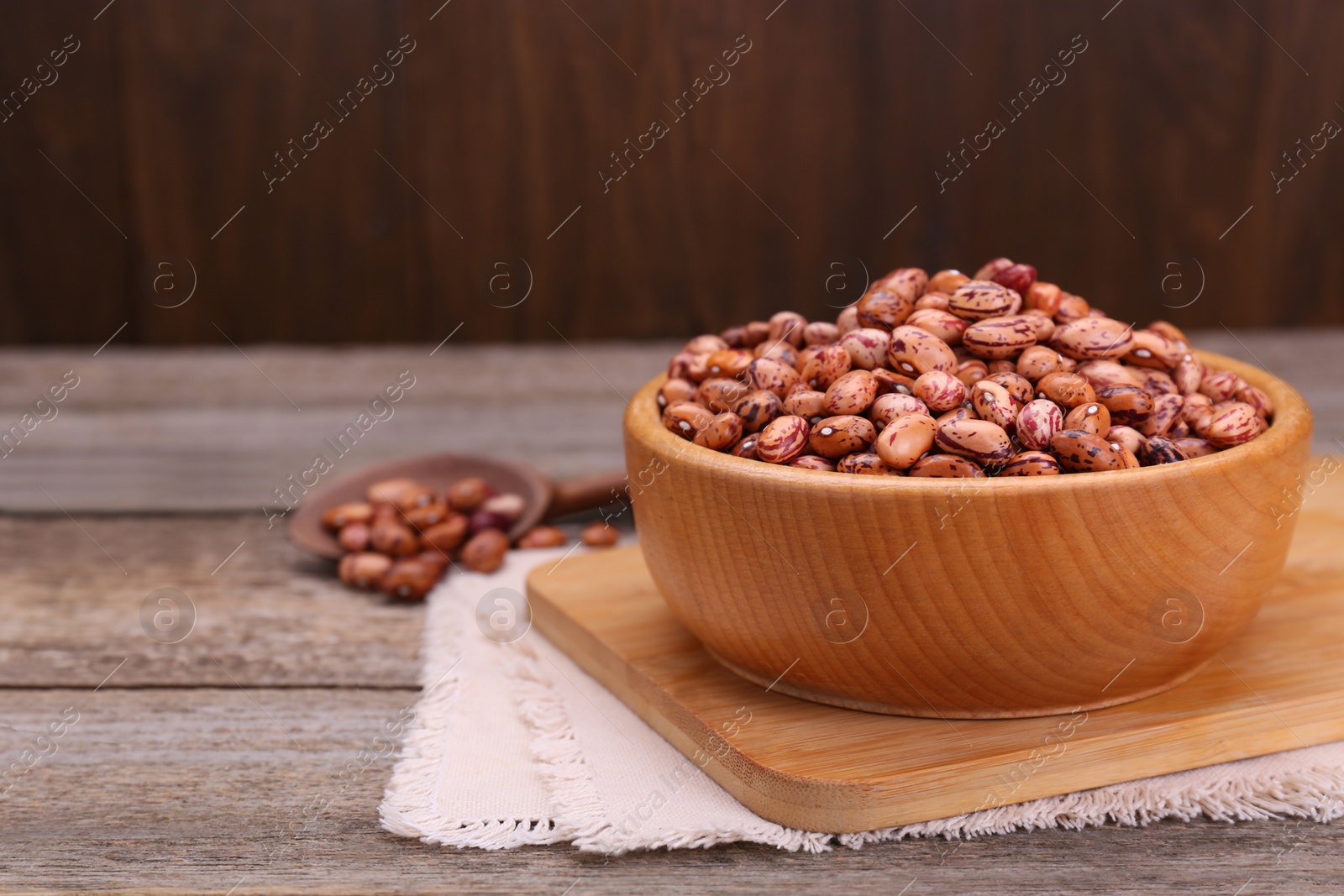 Photo of Bowl with dry kidney beans on old wooden table, closeup. Space for text