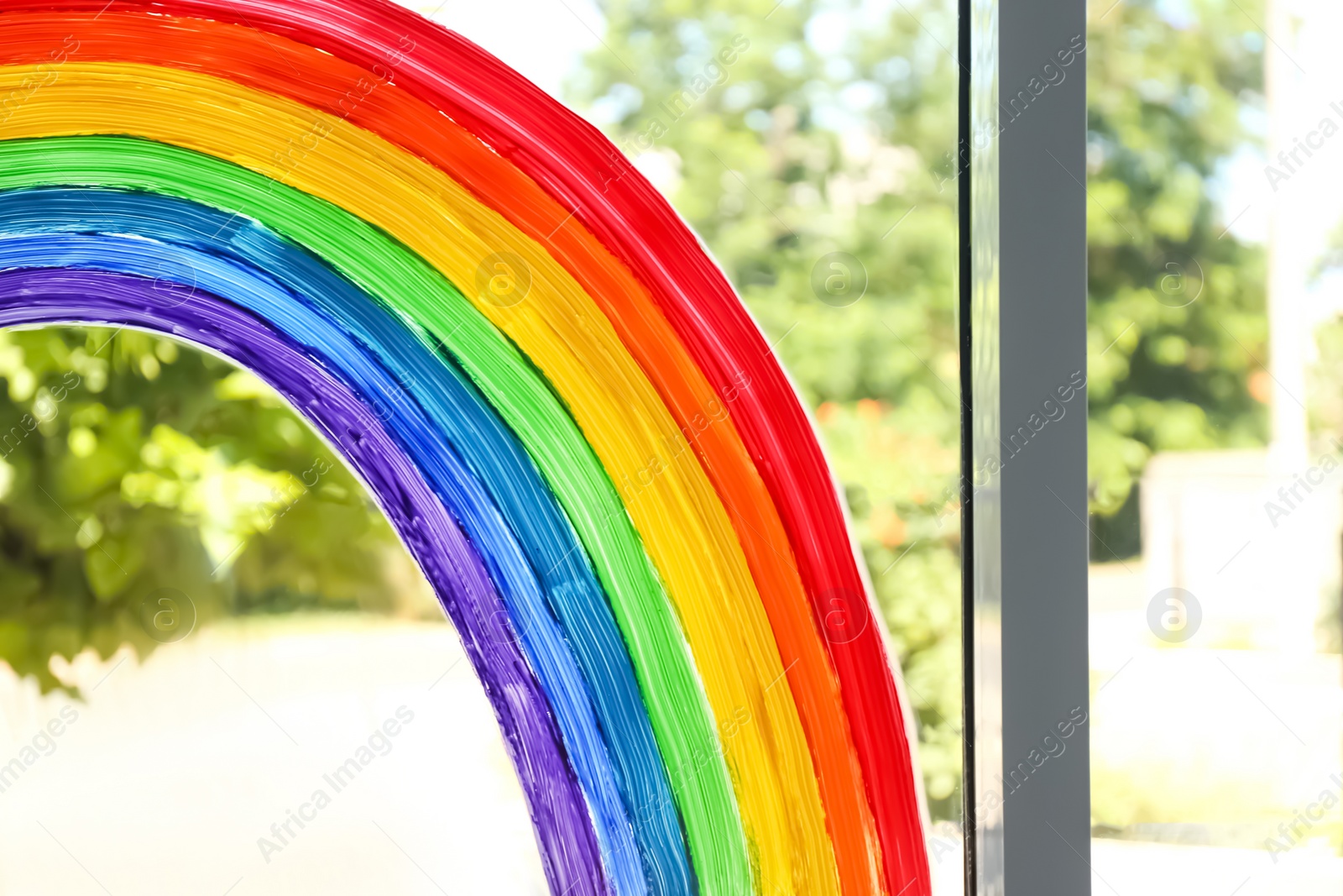 Photo of Painting of rainbow on window, closeup. Stay at home concept