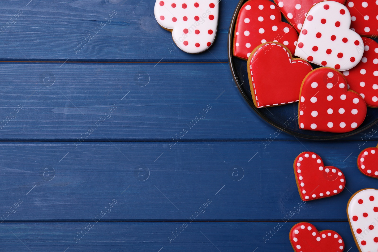 Photo of Glazed heart shaped cookies on blue wooden table, flat lay. Space for text