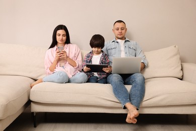 Happy family with gadgets on sofa at home