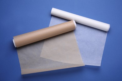 Photo of Rolls of baking paper on blue background, top view