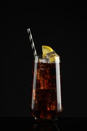 Glass of refreshing soda water with ice cubes and lemon slice on black background