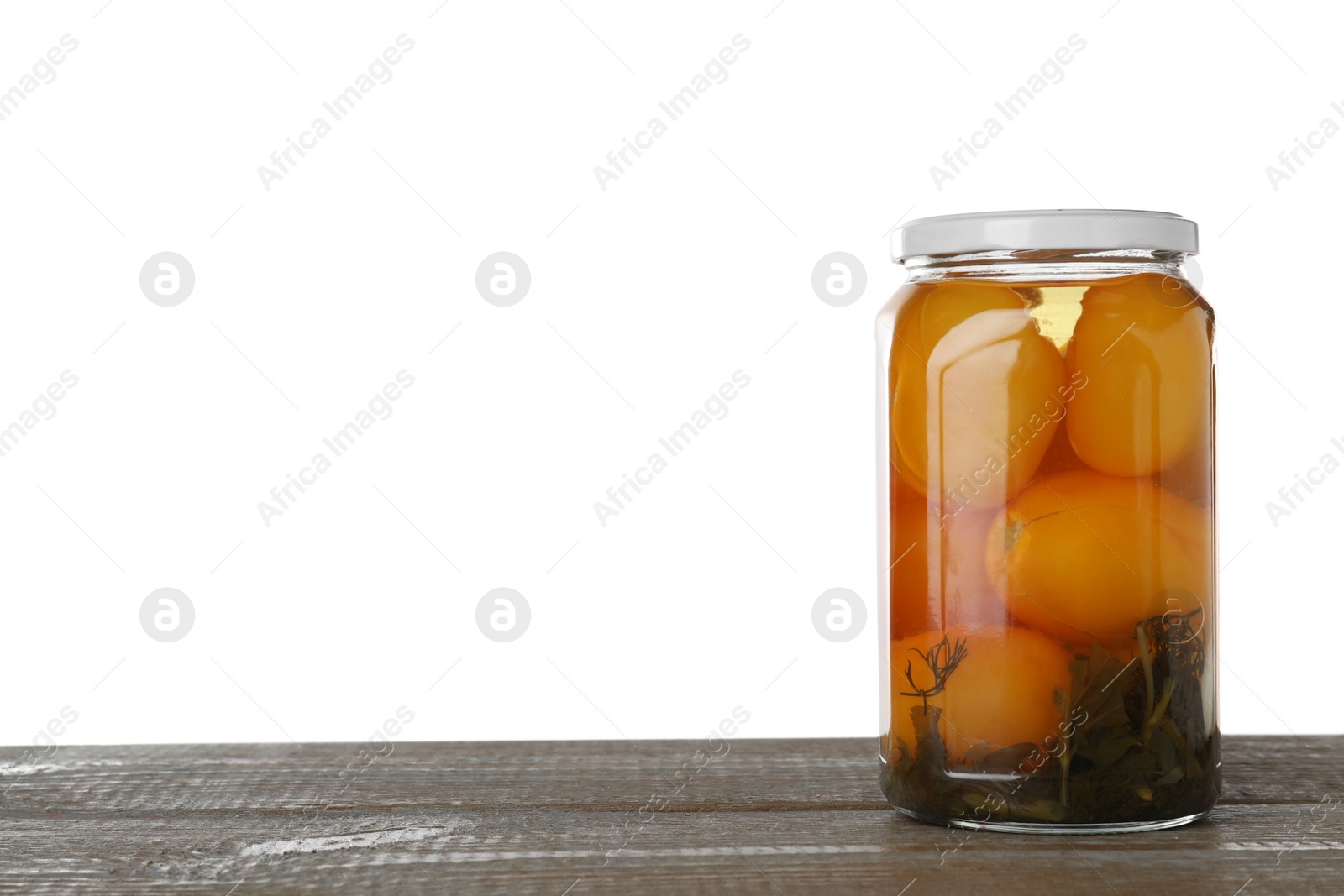 Photo of Jar of pickled yellow tomatoes on wooden table against white background. Space for text