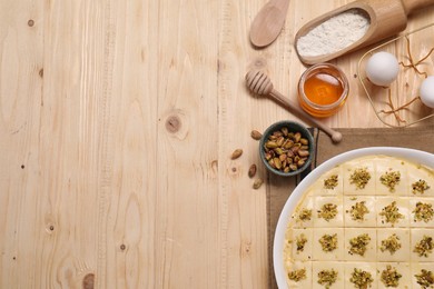 Photo of Making delicious baklava. Raw dough with ingredients on wooden table, flat lay. Space for text