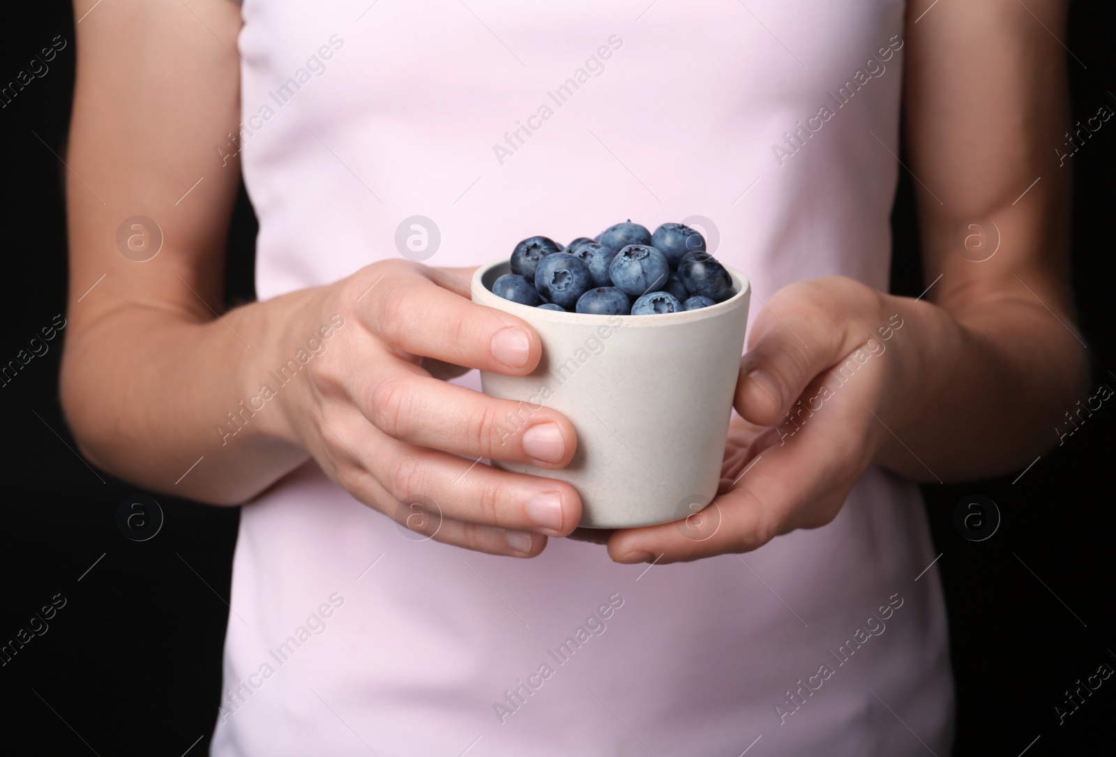 Photo of Woman holding crockery with juicy fresh blueberries in hands, closeup view