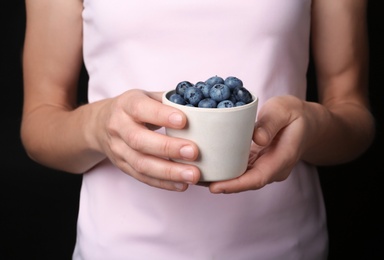 Woman holding crockery with juicy fresh blueberries in hands, closeup view